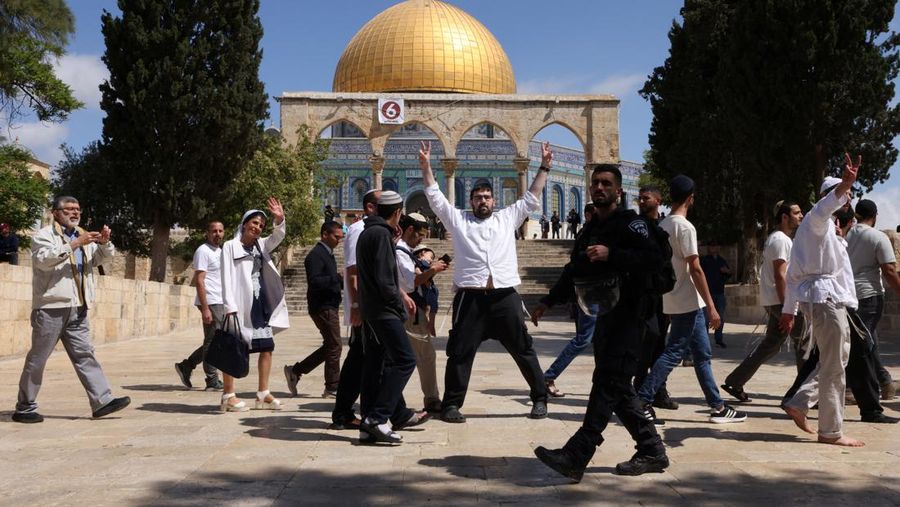 Warga memberi isyarat saat pasukan keamanan Israel mengamankan area di kompleks Masjid Al-Aqsa di Kota Tua Yerusalem, Kamis (5/4/2022). (REUTERS/Ammar Awad)