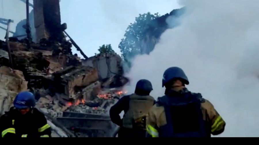 Petugas pemadam kebakaran bekerja di dekat puing-puing yang terbakar, setelah sebuah gedung sekolah hancur akibat bom yang dilakukan oleh Rusia di desa Bilohorivka, Luhansk, Ukraina, Minggu (8/5/2022). (Luhansk Regional Military-Civil Administration/Handout via REUTERS)