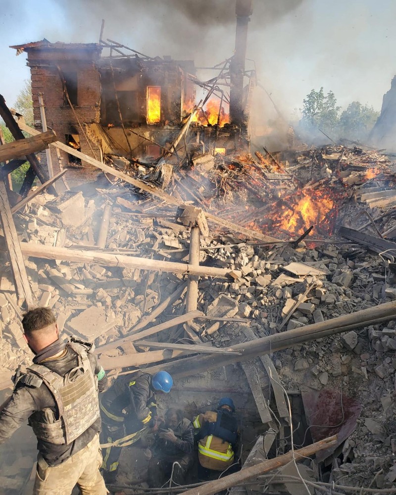 Petugas pemadam kebakaran bekerja di dekat puing-puing yang terbakar, setelah sebuah gedung sekolah hancur akibat bom yang dilakukan oleh Rusia di desa Bilohorivka, Luhansk, Ukraina, Minggu (8/5/2022). (Luhansk Regional Military-Civil Administration/Handout via REUTERS)