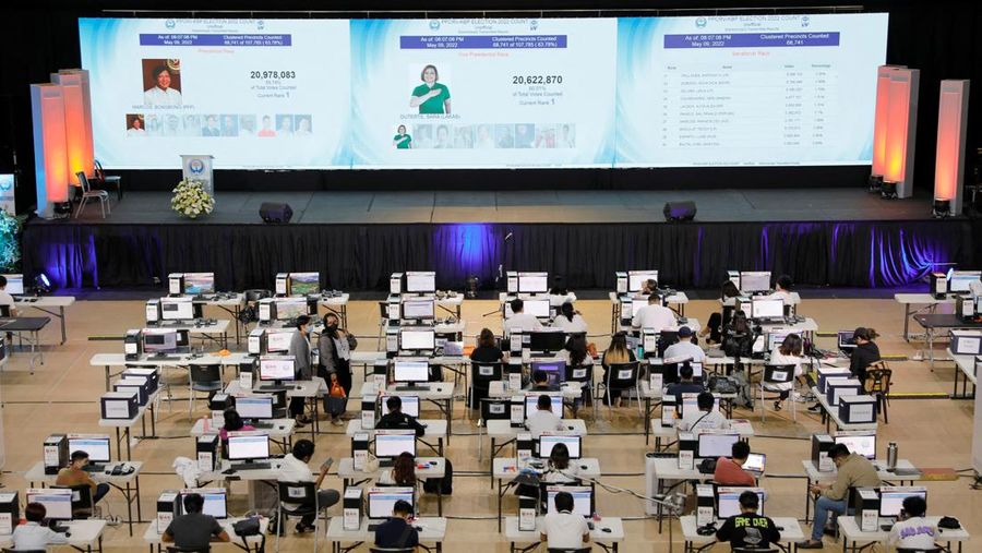 Staff members sit at computers as screens show an official quick-count of the national election at a command center of the Parish Pastoral Council for Responsible Voting (PPCRV), the election watchdog organization in Manila, Philippines, May 9, 2022. REUTERS/Willy Kurniawan