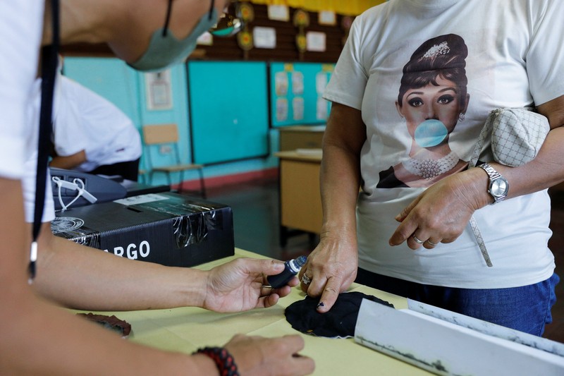 Staff members sit at computers as screens show an official quick-count of the national election at a command center of the Parish Pastoral Council for Responsible Voting (PPCRV), the election watchdog organization in Manila, Philippines, May 9, 2022. REUTERS/Willy Kurniawan