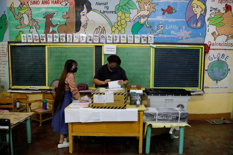 Staff members sit at computers as screens show an official quick-count of the national election at a command center of the Parish Pastoral Council for Responsible Voting (PPCRV), the election watchdog organization in Manila, Philippines, May 9, 2022. REUTERS/Willy Kurniawan