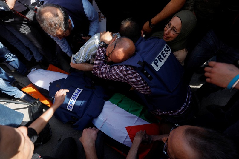 PALESTINIANS-ISRAEL/ Palestinian gunmen carry the body of Al Jazeera reporter Shireen Abu Akleh, who was killed by Israeli army gunfire during an Israeli raid, the Qatar-based news channel said, in Jenin in the Israeli-occupied West Bank May 11, 2022. Israeli military said Abu Akleh may have been shot by Palestinians as they clashed with its troops. REUTERS/Mohamad Torokman
