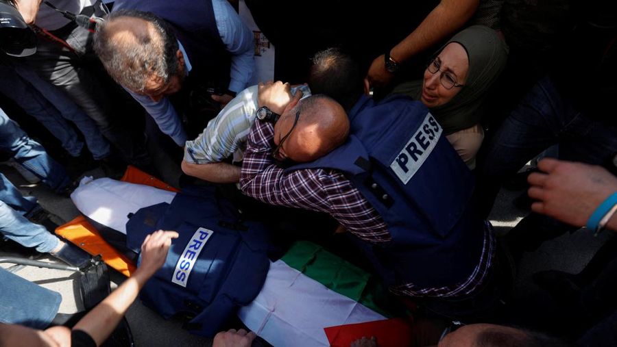 Palestinian gunmen carry the body of Al Jazeera reporter Shireen Abu Akleh, who was killed by Israeli army gunfire during an Israeli raid, the Qatar-based news channel said, in Jenin in the Israeli-occupied West Bank May 11, 2022. Israeli military said Abu Akleh may have been shot by Palestinians as they clashed with its troops. REUTERS/Mohamad Torokman