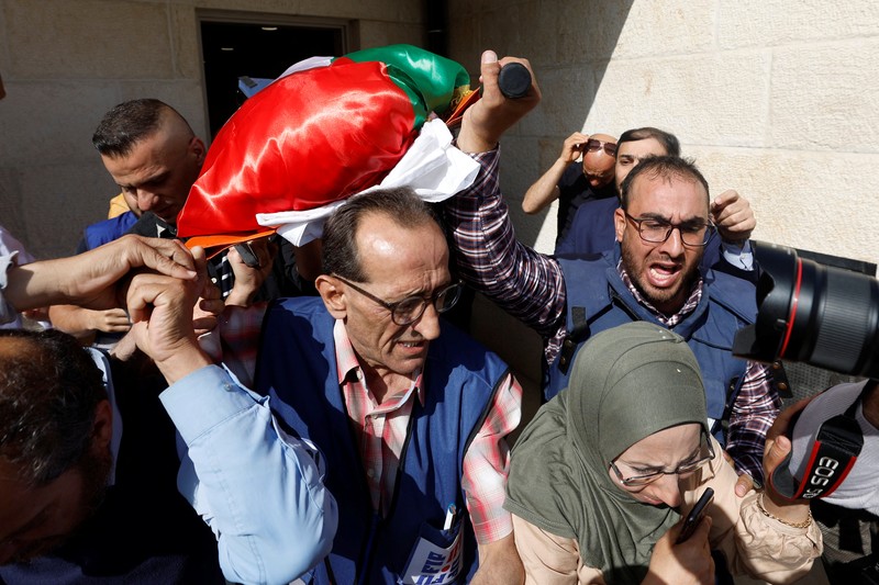 PALESTINIANS-ISRAEL/ Palestinian gunmen carry the body of Al Jazeera reporter Shireen Abu Akleh, who was killed by Israeli army gunfire during an Israeli raid, the Qatar-based news channel said, in Jenin in the Israeli-occupied West Bank May 11, 2022. Israeli military said Abu Akleh may have been shot by Palestinians as they clashed with its troops. REUTERS/Mohamad Torokman