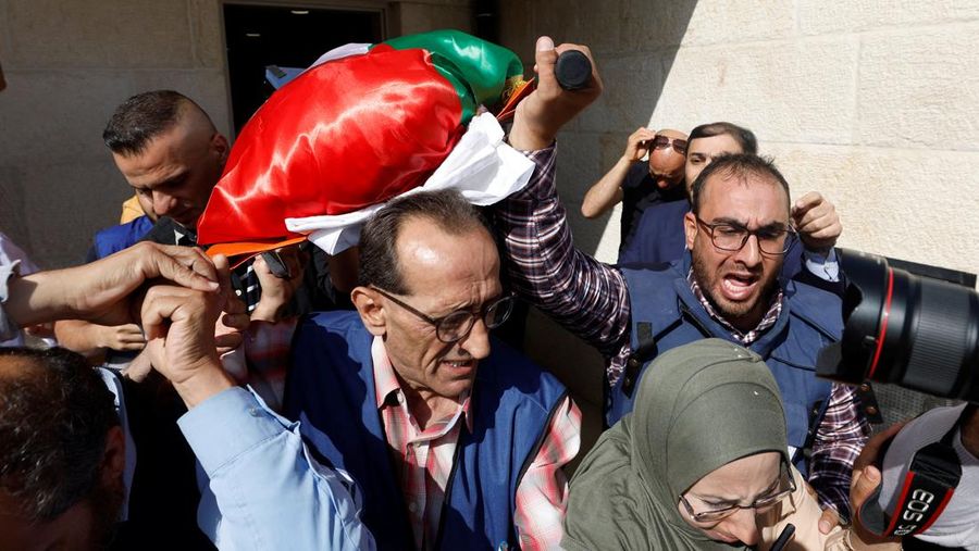 Palestinian gunmen carry the body of Al Jazeera reporter Shireen Abu Akleh, who was killed by Israeli army gunfire during an Israeli raid, the Qatar-based news channel said, in Jenin in the Israeli-occupied West Bank May 11, 2022. Israeli military said Abu Akleh may have been shot by Palestinians as they clashed with its troops. REUTERS/Mohamad Torokman