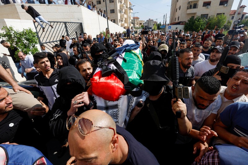 PALESTINIANS-ISRAEL/ Palestinian gunmen carry the body of Al Jazeera reporter Shireen Abu Akleh, who was killed by Israeli army gunfire during an Israeli raid, the Qatar-based news channel said, in Jenin in the Israeli-occupied West Bank May 11, 2022. Israeli military said Abu Akleh may have been shot by Palestinians as they clashed with its troops. REUTERS/Mohamad Torokman