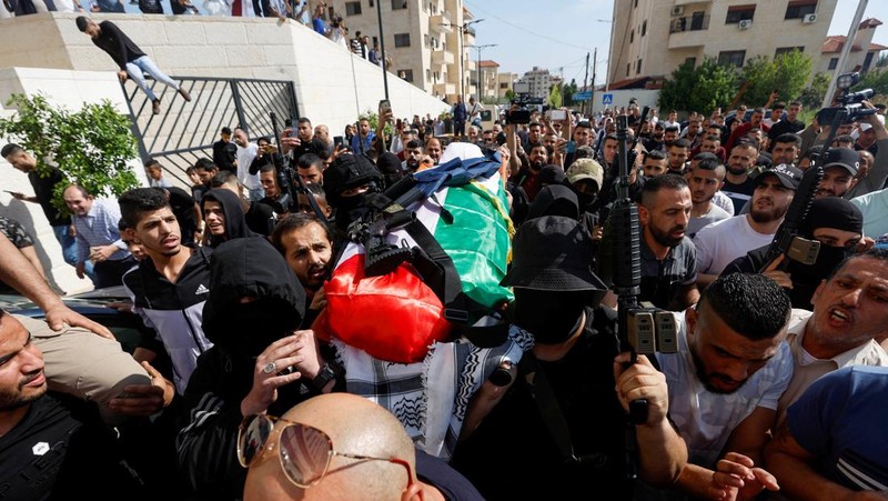 Palestinian gunmen carry the body of Al Jazeera reporter Shireen Abu Akleh, who was killed by Israeli army gunfire during an Israeli raid, the Qatar-based news channel said, in Jenin in the Israeli-occupied West Bank May 11, 2022. Israeli military said Abu Akleh may have been shot by Palestinians as they clashed with its troops. REUTERS/Mohamad Torokman