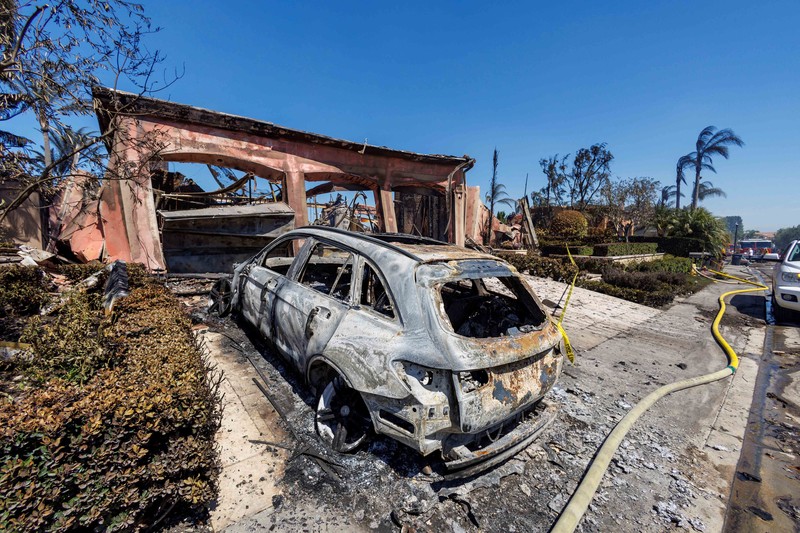 A firefighter sprays water on the remains of a burned-out home after a fast-moving wildfire ripped through an affluent neighborhood in Laguna Niguel, California, U.S., May 12, 2022. REUTERS/Mike Blake