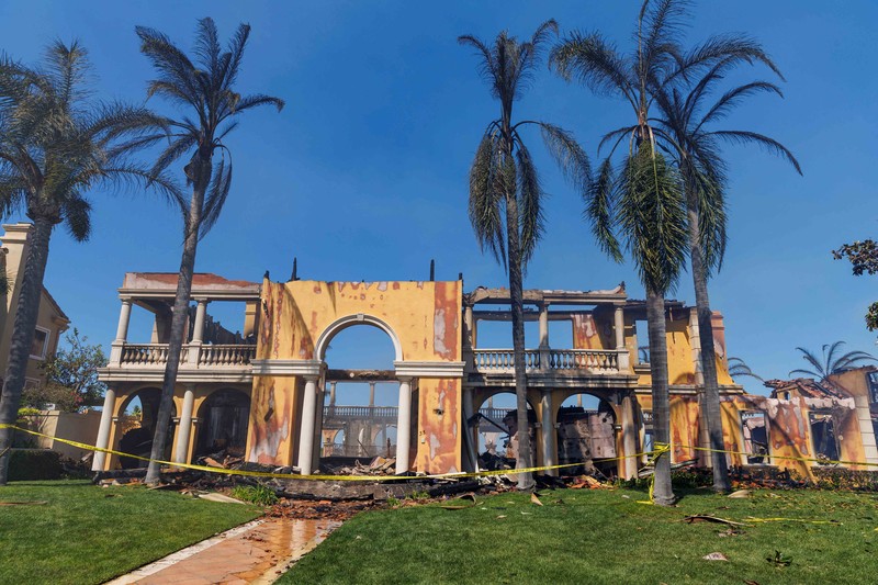 USA-WILDFIRE/CALIFORNIA A firefighter sprays water on the remains of a burned-out home after a fast-moving wildfire ripped through an affluent neighborhood in Laguna Niguel, California, U.S., May 12, 2022. REUTERS/Mike Blake