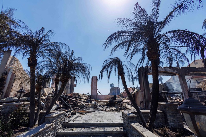 A firefighter sprays water on the remains of a burned-out home after a fast-moving wildfire ripped through an affluent neighborhood in Laguna Niguel, California, U.S., May 12, 2022. REUTERS/Mike Blake