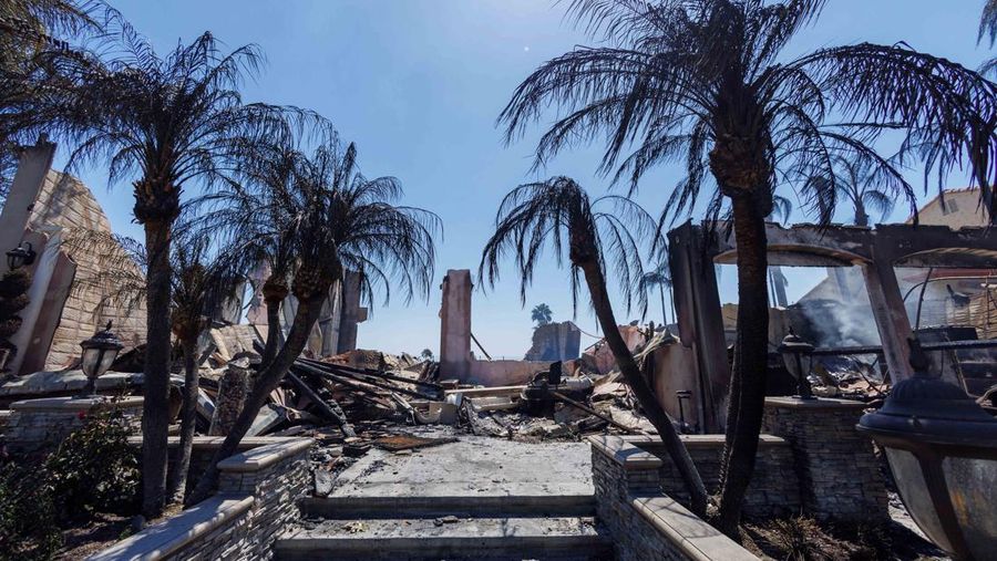 A firefighter sprays water on the remains of a burned-out home after a fast-moving wildfire ripped through an affluent neighborhood in Laguna Niguel, California, U.S., May 12, 2022. REUTERS/Mike Blake