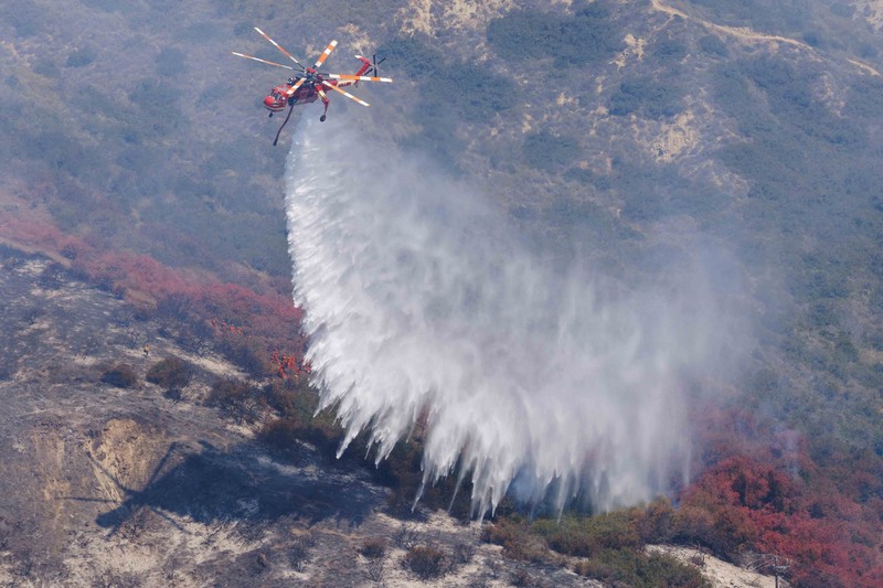 A firefighter sprays water on the remains of a burned-out home after a fast-moving wildfire ripped through an affluent neighborhood in Laguna Niguel, California, U.S., May 12, 2022. REUTERS/Mike Blake