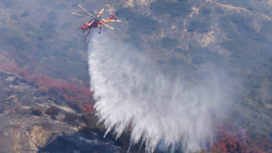 A firefighter sprays water on the remains of a burned-out home after a fast-moving wildfire ripped through an affluent neighborhood in Laguna Niguel, California, U.S., May 12, 2022. REUTERS/Mike Blake
