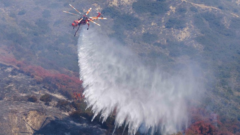 A firefighter sprays water on the remains of a burned-out home after a fast-moving wildfire ripped through an affluent neighborhood in Laguna Niguel, California, U.S., May 12, 2022. REUTERS/Mike Blake