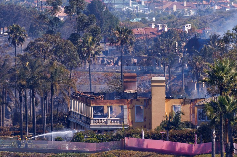 USA-WILDFIRE/CALIFORNIA A firefighter sprays water on the remains of a burned-out home after a fast-moving wildfire ripped through an affluent neighborhood in Laguna Niguel, California, U.S., May 12, 2022. REUTERS/Mike Blake