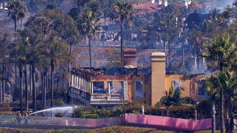 A firefighter sprays water on the remains of a burned-out home after a fast-moving wildfire ripped through an affluent neighborhood in Laguna Niguel, California, U.S., May 12, 2022. REUTERS/Mike Blake