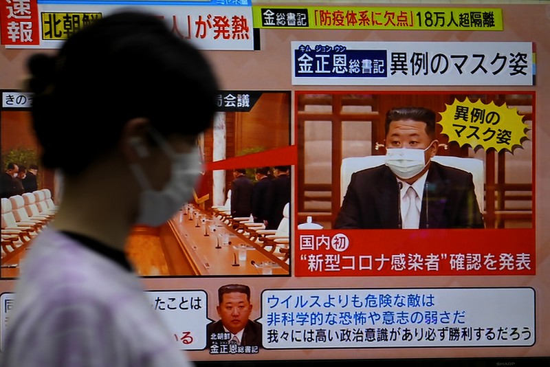Virus Outbreak Japan North Korea A passerby walks past a screen displaying an image of North Korean leader Kim Jong Un wearing a face mask on a TV news program in Tokyo, Friday, May 13, 2022. North Korea imposed a nationwide lockdown Thursday to control its first acknowledged COVID-19 outbreak after holding for more than two years to a widely doubted claim of a perfect record keeping out the virus that has spread to nearly every place in the world.(AP Photo/Shuji Kajiyama)