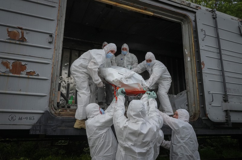 Ukrainian servicemen collect bodies of Russian soldiers to load into a railway refrigerator carriage in Kyiv, Ukraine, Friday, May 13, 2022. (AP Photo/Efrem Lukatsky)