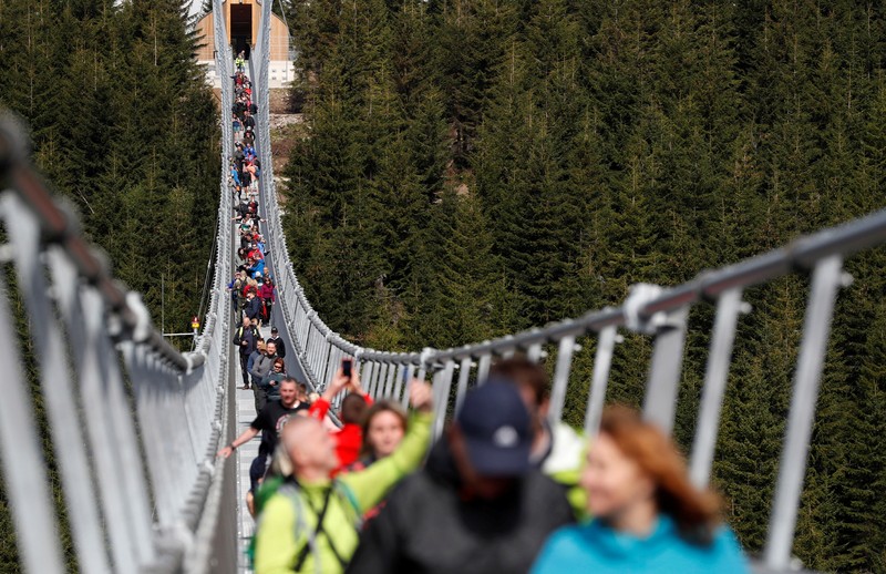 People walk across the newly-built world's longest suspension bridge after its official opening in the mountain resort of Dolni Morava, Czech Republic, May 13, 2022. REUTERS/David W Cerny *** Local Caption *** CAPTION TEST 01