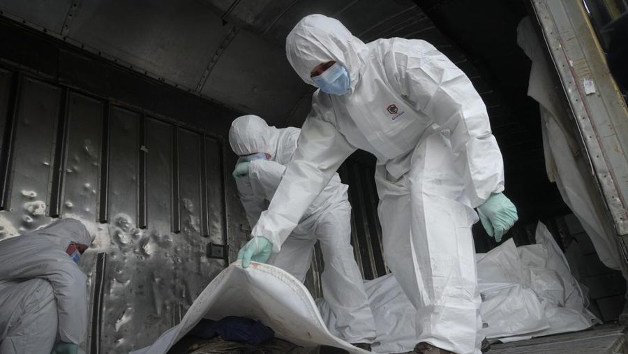 Ukrainian servicemen collect bodies of Russian soldiers to load into a railway refrigerator carriage in Kyiv, Ukraine, Friday, May 13, 2022. (AP Photo/Efrem Lukatsky)