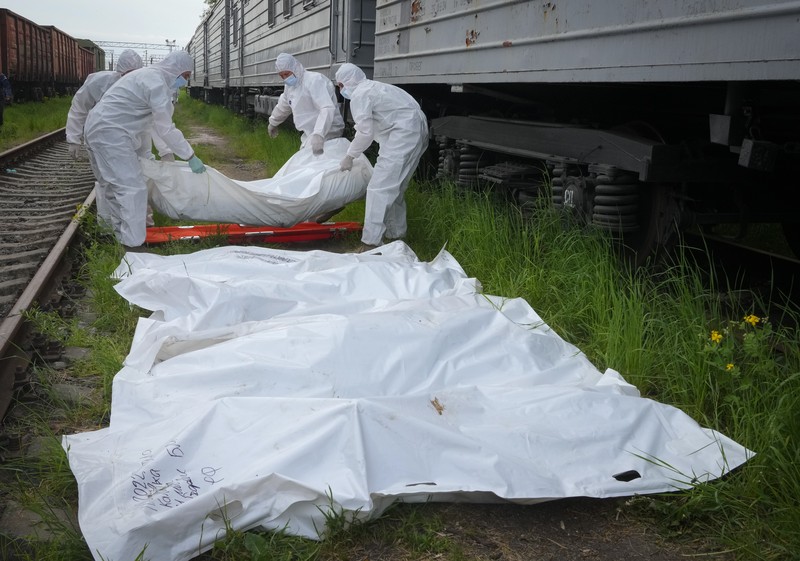 Ukrainian servicemen collect bodies of Russian soldiers to load into a railway refrigerator carriage in Kyiv, Ukraine, Friday, May 13, 2022. (AP Photo/Efrem Lukatsky)