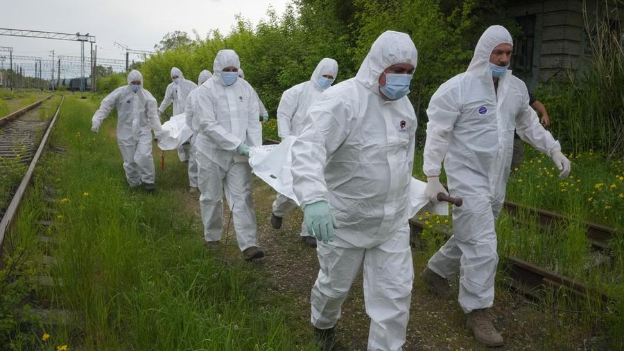 Ukrainian servicemen collect bodies of Russian soldiers to load into a railway refrigerator carriage in Kyiv, Ukraine, Friday, May 13, 2022. (AP Photo/Efrem Lukatsky)