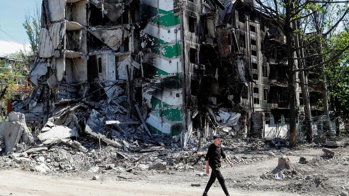 UKRAINE-CRISIS/MARIUPOL A man walks past a residential building destroyed during Ukraine-Russia conflict in the southern port city of Mariupol, Ukraine May 12, 2022. REUTERS/Alexander Ermochenko
