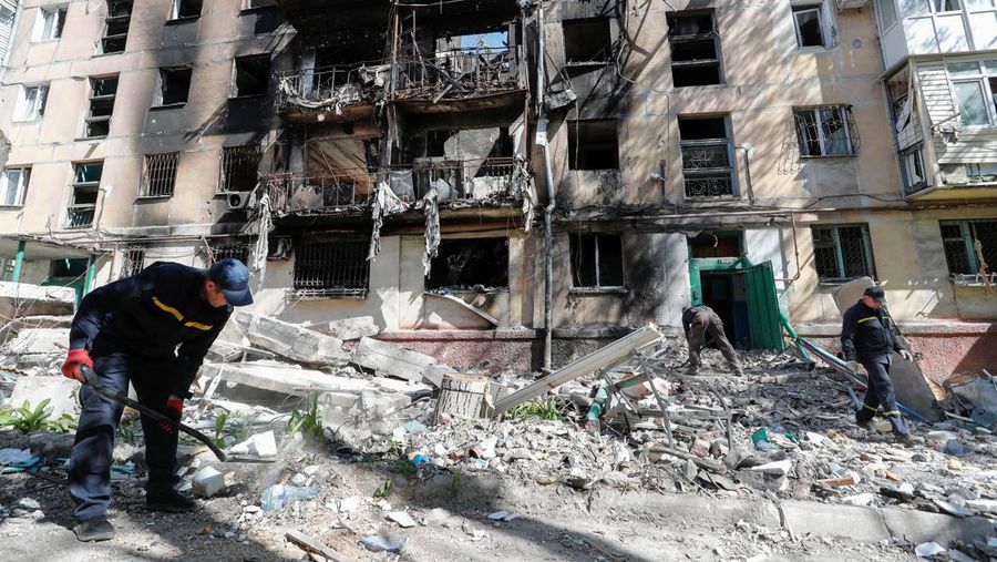 Workers remove debris in front of a building destroyed during Ukraine-Russia conflict in the southern port city of Mariupol, Ukraine May 12, 2022. REUTERS/Alexander Ermochenko