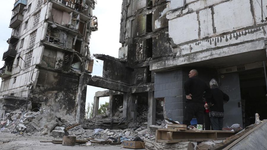 Local residents stand at the side of damaged during a heavy fighting buildings in Mariupol, in territory under the government of the Donetsk People's Republic, eastern Ukraine, Friday, May 13, 2022. (AP Photo)
