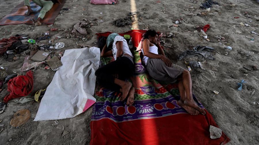 Orang-orang beristirahat di bawah jembatan di dasar Sungai Yamuna pada hari musim panas di New Delhi. (Anadolu Agency via Getty Images/Anadolu Agency)
