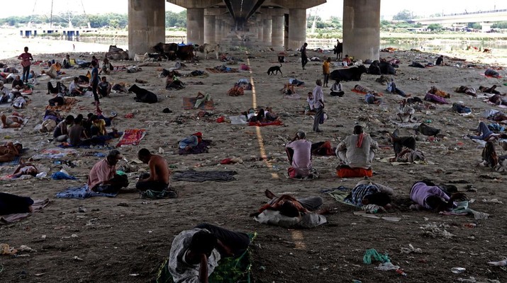 Orang-orang beristirahat di bawah jembatan di dasar Sungai Yamuna pada hari musim panas di New Delhi. (Anadolu Agency via Getty Images/Anadolu Agency)