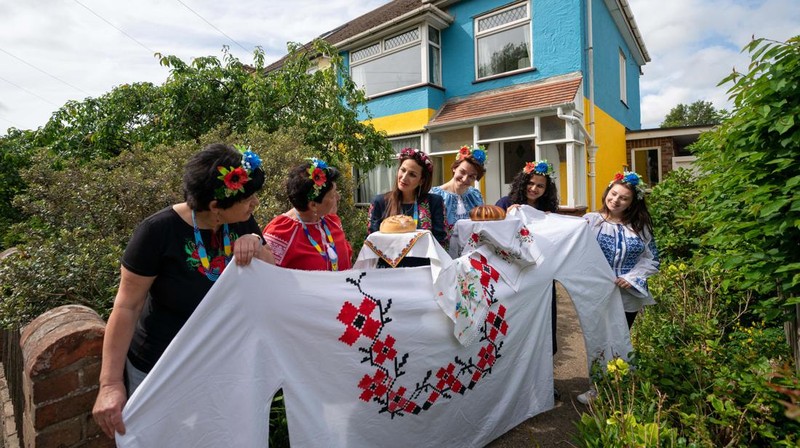 Kristina Korniiuk, 34, (ketiga kanan) yang berasal dari Kyiv dan melarikan diri dari Ukraina setelah invasi Rusia, menandai perayaan Hari Vyshyvanka di Ukraina dengan kemeja tradisional raksasa, di rumah tuan rumahnya Rend Platings (ketiga kiri) di Cambridge . Kristina bergabung dengan rekan sesama Ukrania Anastasiia Romaniuk (kanan) dan saudara perempuan Alla Marich (kiri) dan Iryna Marich (kedua kiri). Tanggal foto: Kamis 19 Mei 2022. (Joe Giddens/PA Images via Getty Images)