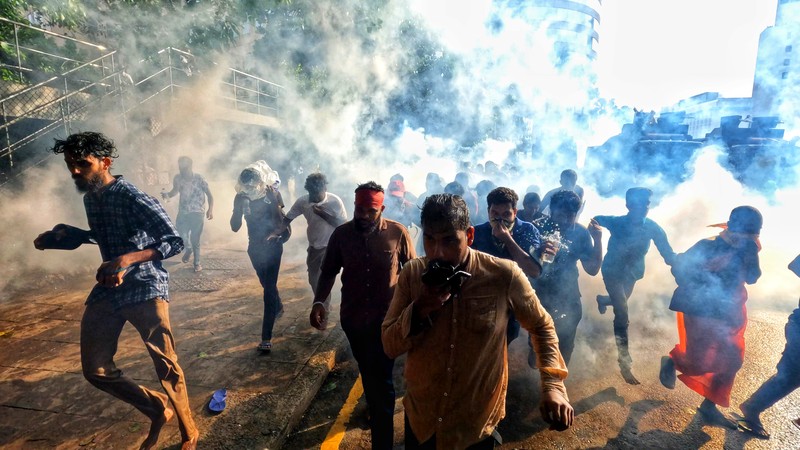Mahasiswa Sri Lanka melarikan diri dari meriam air dan gas air mata saat para pengunjuk rasa bentrok dengan polisi melawan pemerintah di dekat kediaman resmi presiden Gotabaya Rajapaksa di Kolombo, Sri Lanka. (NurPhoto via Getty Images/NurPhoto) Mahasiswa Sri Lanka melarikan diri dari meriam air dan gas air mata saat para pengunjuk rasa bentrok dengan polisi melawan pemerintah di dekat kediaman resmi presiden Gotabaya Rajapaksa di Kolombo, Sri Lanka. (NurPhoto via Getty Images/NurPhoto)