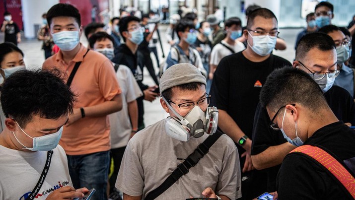 Orang-orang yang memakai masker mengantre di pembukaan resmi Apple Store baru di Wuhan International Plaza, Wuhan. (SOPA Images/LightRocket via Getty)