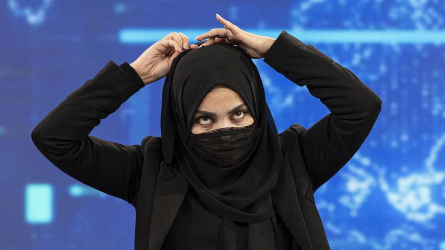 Presenter wanita untuk TOLOnews, Thamina Usmani, bersiap untuk siaran langsungnya di stasiun TV Tolo di Kabul, Afghanistan, Minggu (22/5/2022). Taliban menambah panjang aturan dengan mewajibkan presenter perempuan di Afghanistan menutup wajah saat siaran langsung di televisi. (Photo by WAKIL KOHSAR/AFP via Getty Images)