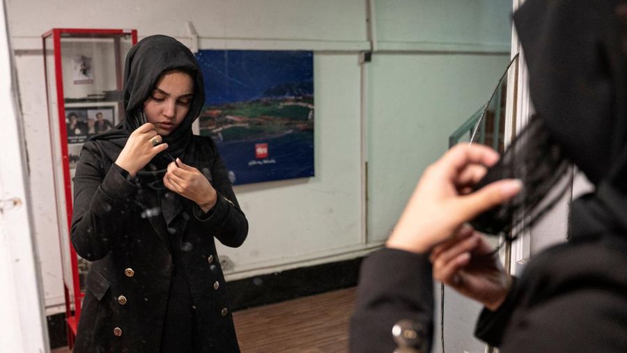 Presenter wanita untuk TOLOnews, Thamina Usmani, bersiap untuk siaran langsungnya di stasiun TV Tolo di Kabul, Afghanistan, Minggu (22/5/2022). Taliban menambah panjang aturan dengan mewajibkan presenter perempuan di Afghanistan menutup wajah saat siaran langsung di televisi. (Photo by WAKIL KOHSAR/AFP via Getty Images)