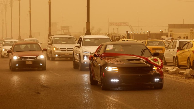 Sejumlah warga beraktivtas saat badai pasir di Najaf, Irak, Senin (23/5/2022). (REUTERS/Alaa Al-Marjani)