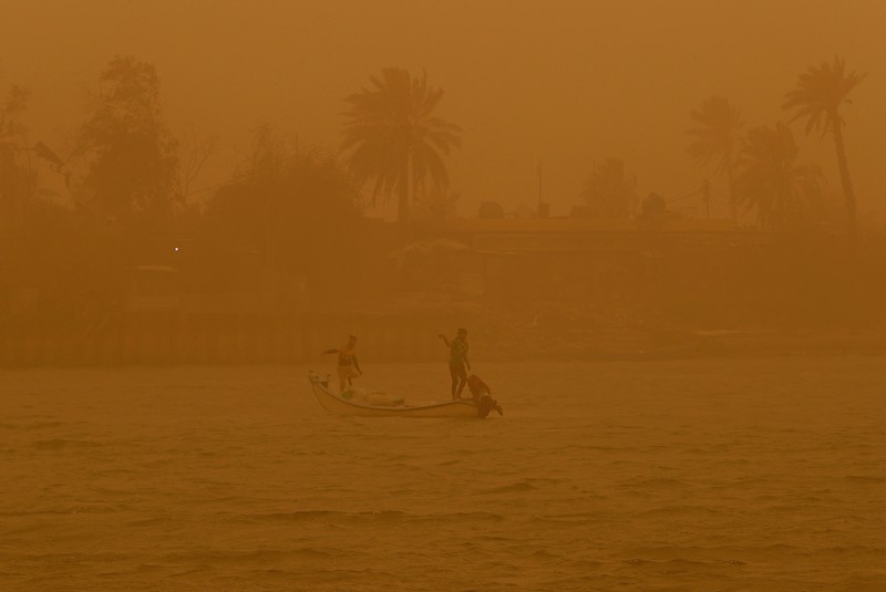 Sejumlah warga beraktivtas saat badai pasir di Najaf, Irak, Senin (23/5/2022). (REUTERS/Alaa Al-Marjani)