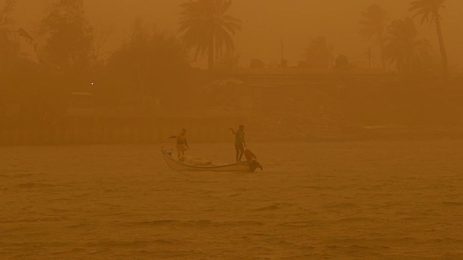 Sejumlah warga beraktivtas saat badai pasir di Najaf, Irak, Senin (23/5/2022). (REUTERS/Alaa Al-Marjani)