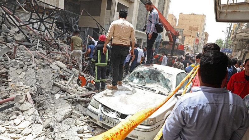 Warga Iran berkumpul di lokasi di mana sebuah bangunan sepuluh lantai runtuh di barat daya kota Abadan, Iran, Senin (23/5/2022).  Kejadian tersebut menyebabkan beberapa orang meninggal dan sekitar 80 orang terperangkap di bawah reruntuhan ketika sebuah bangunan yang belum selesai roboh di barat daya Iran. (Photo by -/TASNIM NEWS/AFP via Getty Images)