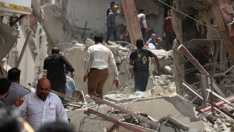 Warga Iran berkumpul di lokasi di mana sebuah bangunan sepuluh lantai runtuh di barat daya kota Abadan, Iran, Senin (23/5/2022).  Kejadian tersebut menyebabkan beberapa orang meninggal dan sekitar 80 orang terperangkap di bawah reruntuhan ketika sebuah bangunan yang belum selesai roboh di barat daya Iran. (Photo by -/TASNIM NEWS/AFP via Getty Images)
