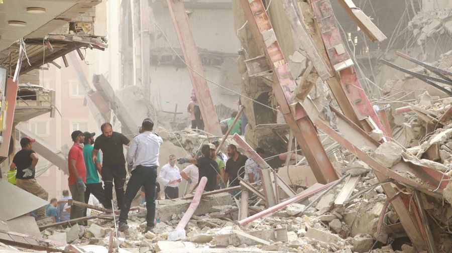 Warga Iran berkumpul di lokasi di mana sebuah bangunan sepuluh lantai runtuh di barat daya kota Abadan, Iran, Senin (23/5/2022).  Kejadian tersebut menyebabkan beberapa orang meninggal dan sekitar 80 orang terperangkap di bawah reruntuhan ketika sebuah bangunan yang belum selesai roboh di barat daya Iran. (Photo by -/TASNIM NEWS/AFP via Getty Images)