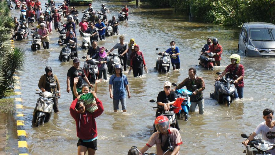 Para pekerja menggunakan perahu untuk meninggalkan pabrik mereka setelah gelombang pasang menghantam garis pantai utara yang melumpuhkan aktivitas pelabuhan di pelabuhan Tanjung Mas di Semarang, Jawa Tengah, Selasa (24/5/2022). (Photo by DAFFA RAMYA KANZUDDIN/AFP via Getty Images)