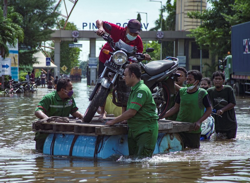 Banjir di area terminal pelabuhan peti kemas Tanjung Emas, Semarang Para pekerja menggunakan perahu untuk meninggalkan pabrik mereka setelah gelombang pasang menghantam garis pantai utara yang melumpuhkan aktivitas pelabuhan di pelabuhan Tanjung Mas di Semarang, Jawa Tengah, Selasa (24/5/2022). (Photo by DAFFA RAMYA KANZUDDIN/AFP via Getty Images)