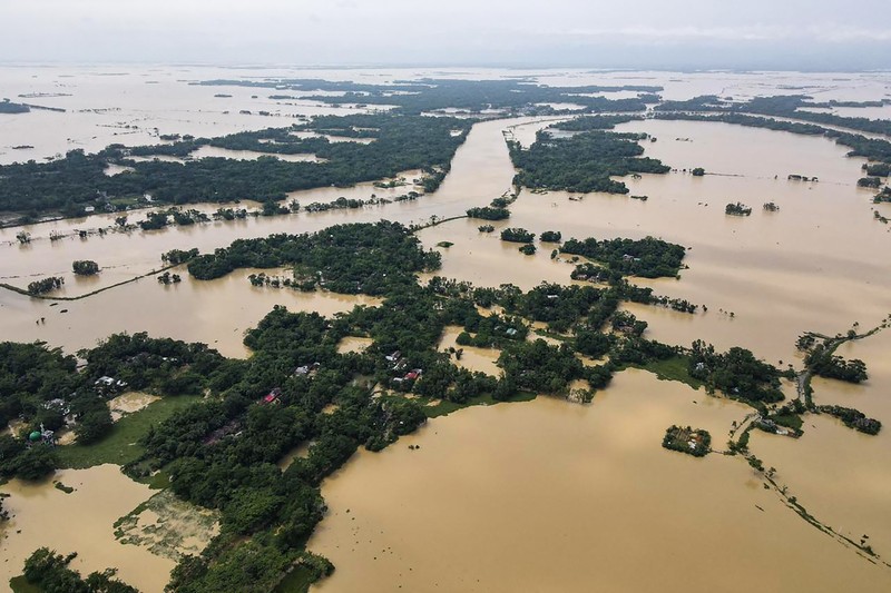 Anak-anak menaiki rakit bambu melewati daerah banjir setelah hujan lebat di distrik Morigaon, negara bagian Assam, India, Minggu (22/5/2022). Banjir adalah ancaman biasa bagi jutaan orang di dataran rendah Bangladesh dan tetangga timur laut India, tetapi banyak ahli mengatakan bahwa perubahan iklim meningkatkan frekuensi, keganasan dan ketidakpastian. (Photo by BIJU BORO/AFP via Getty Images)