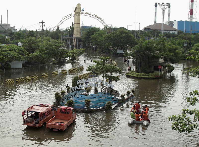 Banjir di area terminal pelabuhan peti kemas Tanjung Emas, Semarang Para pekerja menggunakan perahu untuk meninggalkan pabrik mereka setelah gelombang pasang menghantam garis pantai utara yang melumpuhkan aktivitas pelabuhan di pelabuhan Tanjung Mas di Semarang, Jawa Tengah, Selasa (24/5/2022). (Photo by DAFFA RAMYA KANZUDDIN/AFP via Getty Images)