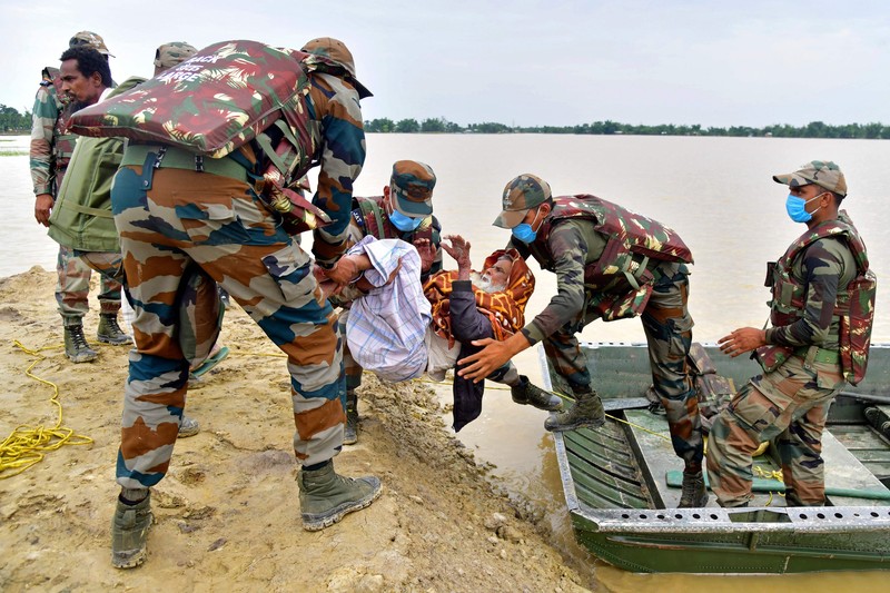 Anak-anak menaiki rakit bambu melewati daerah banjir setelah hujan lebat di distrik Morigaon, negara bagian Assam, India, Minggu (22/5/2022). Banjir adalah ancaman biasa bagi jutaan orang di dataran rendah Bangladesh dan tetangga timur laut India, tetapi banyak ahli mengatakan bahwa perubahan iklim meningkatkan frekuensi, keganasan dan ketidakpastian. (Photo by BIJU BORO/AFP via Getty Images)
