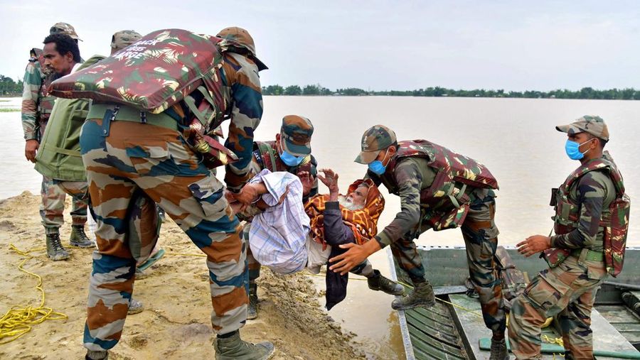 Anak-anak menaiki rakit bambu melewati daerah banjir setelah hujan lebat di distrik Morigaon, negara bagian Assam, India, Minggu (22/5/2022). Banjir adalah ancaman biasa bagi jutaan orang di dataran rendah Bangladesh dan tetangga timur laut India, tetapi banyak ahli mengatakan bahwa perubahan iklim meningkatkan frekuensi, keganasan dan ketidakpastian. (Photo by BIJU BORO/AFP via Getty Images)