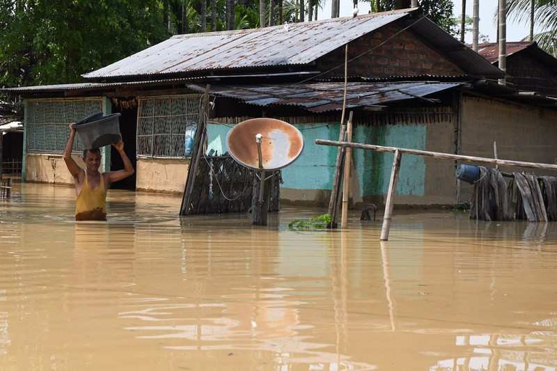 Anak-anak menaiki rakit bambu melewati daerah banjir setelah hujan lebat di distrik Morigaon, negara bagian Assam, India, Minggu (22/5/2022). Banjir adalah ancaman biasa bagi jutaan orang di dataran rendah Bangladesh dan tetangga timur laut India, tetapi banyak ahli mengatakan bahwa perubahan iklim meningkatkan frekuensi, keganasan dan ketidakpastian. (Photo by BIJU BORO/AFP via Getty Images)